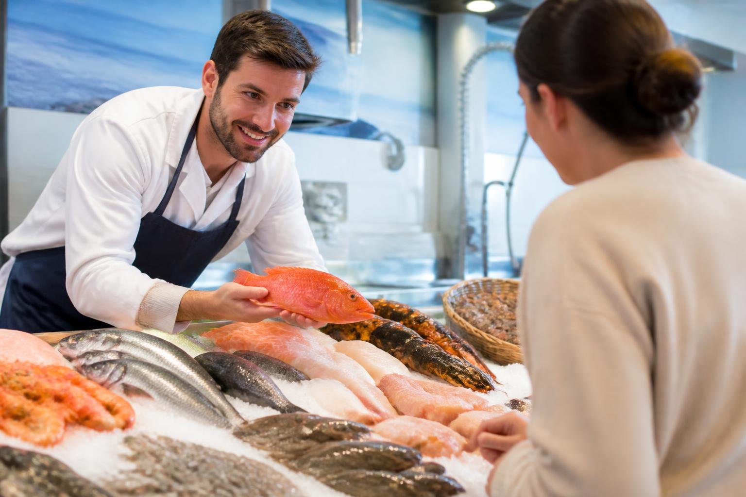 Poissonnier présentant des fruits de mer frais à un client