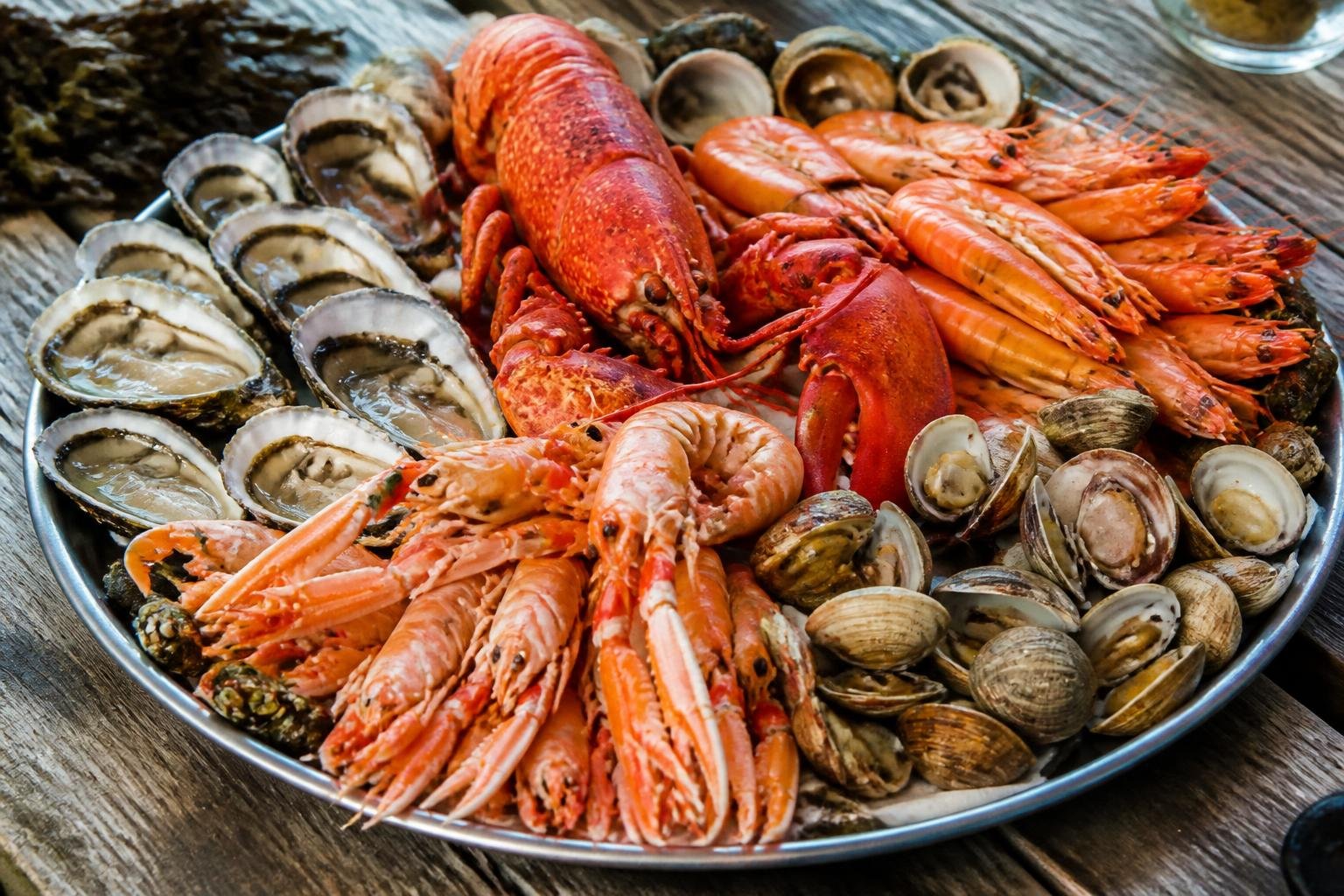Plateau de fruits de mer généreusement garni : huîtres, homard, langoustines et coquillages variés sur fond de bois rustique
